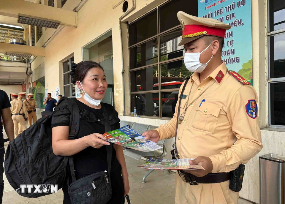 CSGT phát tờ rơi, tuyên truyền đảm bảo an toàn giao thông cho người dân tại khu vực các bến xe. (Ảnh: Phạm Kiên/TTXVN)