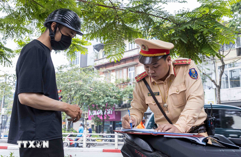 Lực lượng CSGT lập biên bản xử phạt một trường hợp với lỗi vượt đèn đỏ. (Ảnh: Phạm Kiên/TTXVN)