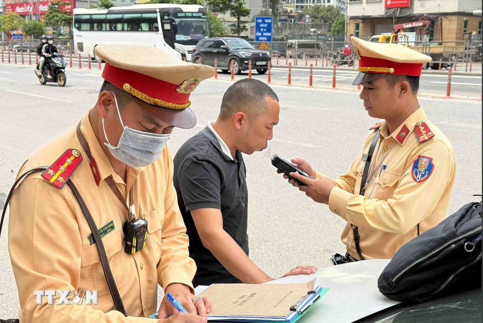 Cán bộ, chiến sỹ đội CSGT số 6 kiểm tra nồng độ cồn đối với tài xế xe khách. (Ảnh: Phạm Kiên/TTXVN)