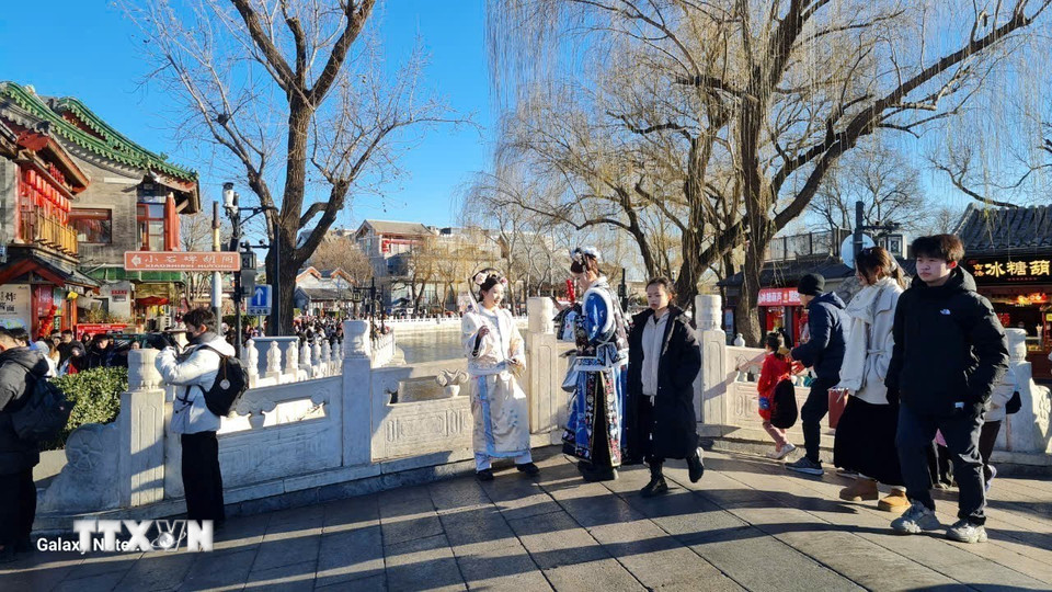 Những thiếu nữ mặc trang phục cổ trang đứng chụp hình trên cầu Ngân Đĩnh - một cây cầu vòm bằng đá nằm giữa Hậu Hải và Tiền Hải. (Ảnh: Quang Hưng/TTXVN)