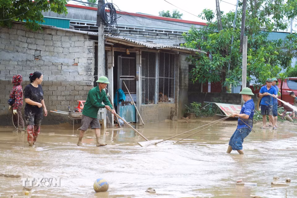 Người dân hỗ trợ nhau kéo bùn đất trên quốc lộ 7. (Ảnh: Xuân Tiến/TTXVN)