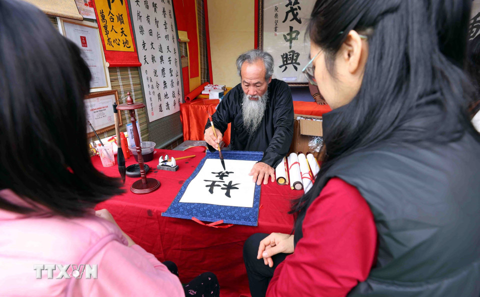 Xin chữ đầu năm tại khu di tích Văn Miếu-Quốc Tử Giám với ước vọng con cái học hành, thi cử đỗ đạt và gặp nhiều may mắn cũng là nét đẹp truyền thống của người dân Thủ đô mỗi dịp du Xuân. (Ảnh: Phạm Kiên/TTXVN)