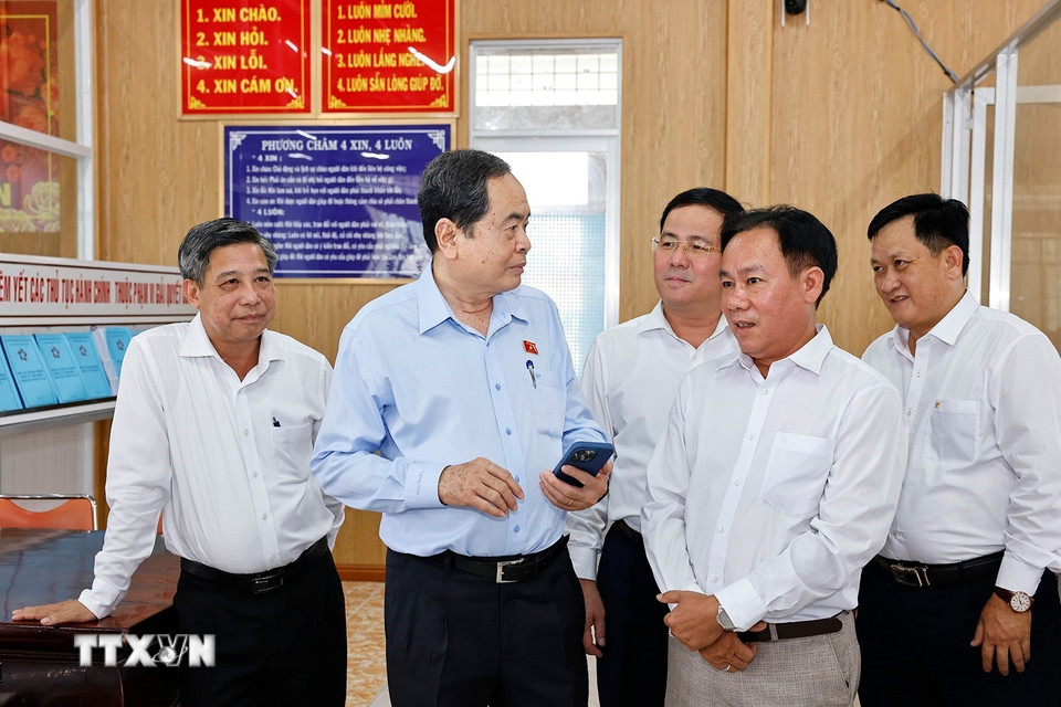 Chủ tịch Quốc hội Trần Thanh Mẫn trao đổi với cán bộ Trung tâm phục vụ hành chính công xã Vị Thủy về sử dụng công nghệ trên điện thoại. (Ảnh: Doãn Tấn/TTXVN)