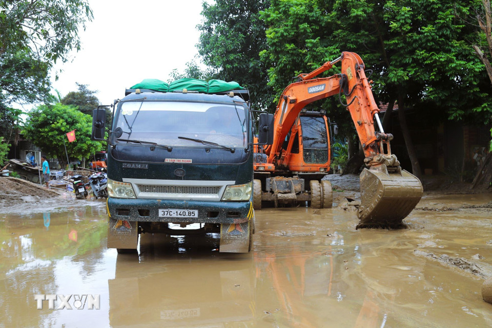 Múc bùn đất, sình lầy giải phóng điểm ngập trên tuyến quốc lộ 7. (Ảnh: Xuân Tiến/TTXVN)