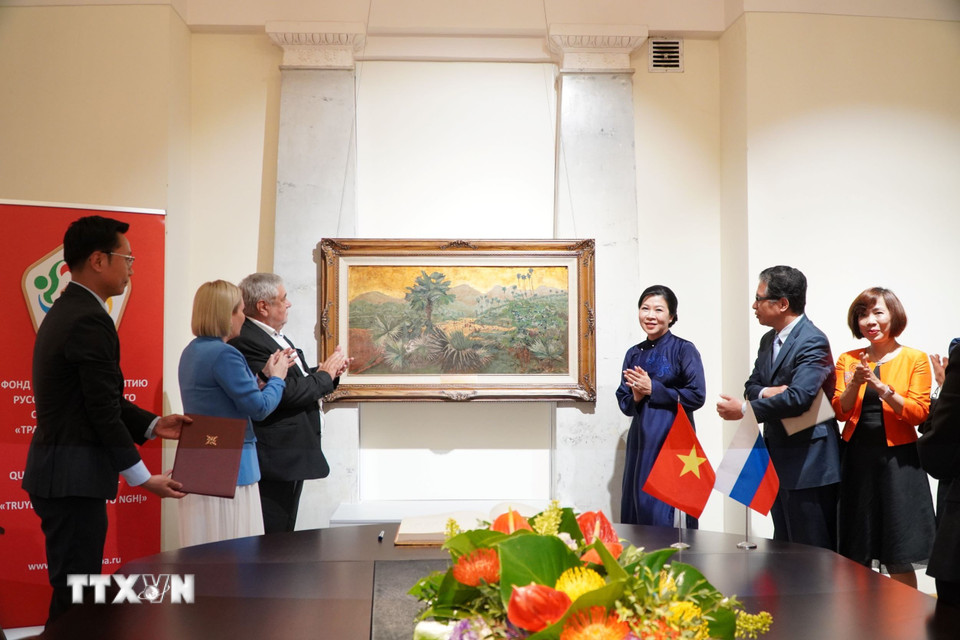 Phu nhân Ngô Phương Ly tặng bức tranh “Những đồi cọ” của cố họa sỹ Phan Kế An. (Ảnh: Tâm Hằng/TTXVN)