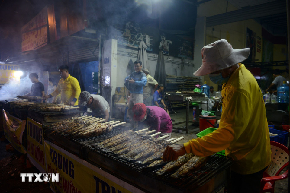 Tối 6/2, phố cá lóc nướng trên đường Tân Kỳ-Tân Quý luôn rực lửa, khói nghi ngút. (Ảnh: Mạnh Linh/TTXVN)