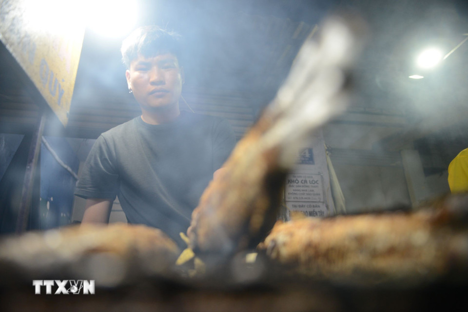 Nhân viên tất bật nướng cá xuyên đêm cho Ngày vía Thần Tài, mùng 10 tháng Giêng. (Ảnh: Mạnh Linh/TTXVN)
