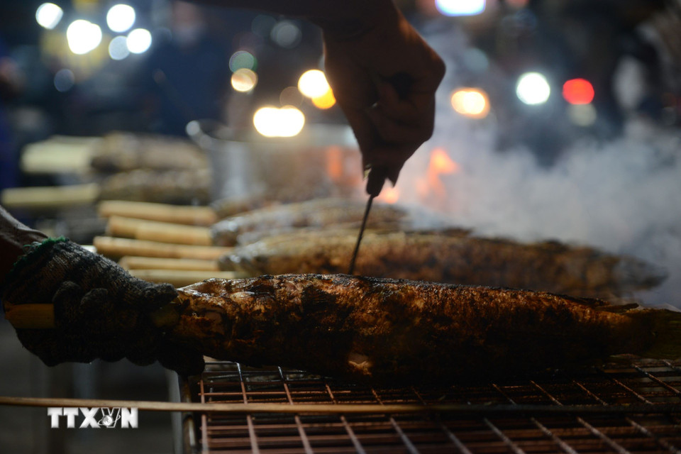 Để có một con cá lóc nướng vàng ươm, người nướng phải khéo léo, trở tay đều để cá không bị cháy. (Ảnh: Mạnh Linh/TTXVN)