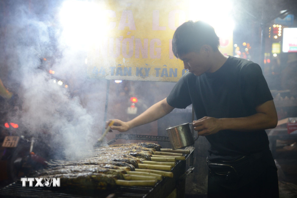 Tối 6/2, phố cá lóc nướng trên đường Tân Kỳ-Tân Quý luôn rực lửa, khói nghi ngút. (Ảnh: Mạnh Linh/TTXVN)