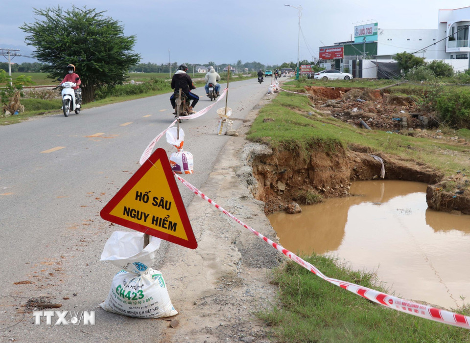 Lực lượng chức năng của xã Ninh Phước đặt biển báo nguy hiểm để người và phương tiện lưu thông cảnh giác phòng tránh tuyến đường 703 bị sạt lở. (Ảnh: Công Thử/TTXVN)