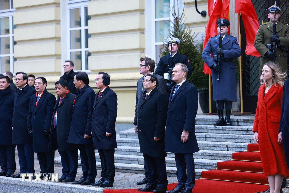 Thủ tướng Phạm Minh Chính và Thủ tướng Cộng hòa Ba Lan Donald Tusk nghe quân nhạc cử Quốc thiều hai nước. (Ảnh: Dương Giang/TTXVN)