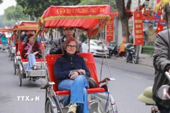 Du khách nước ngoài thích thú với khí hậu mát lạnh của Thủ đô Hà Nội. (Ảnh: Phan Phương/TTXVN)