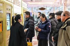 Khách hàng chờ bán đồ trang sức bằng vàng tại một máy bán vàng tự động đặt trong một trung tâm mua sắm ở Thượng Hải. (Ảnh: AFP)