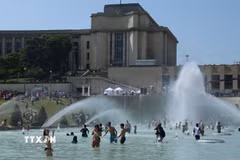 Người dân tránh nóng tại đài phun nước ở Paris, Pháp. (Ảnh: THX/TTXVN)