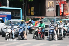 Khẩu trang, áo chống nắng là những thứ không thể thiếu cảu người dân ở Hà Nội khi tham gia giao thông trong những ngày nắng nóng. (Ảnh: Lê Đông/TTXVN)