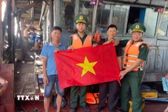Hội viên Nghiệp đoàn nghề cá, tổ viên tổ đoàn kết trên biển thành phố Đà Nẵng nhận cờ Tổ quốc do Đồn biên phòng cửa khẩu cảng Kỳ Hà trao tặng. (Ảnh: Đoàn Hữu Trung/TTXVN)