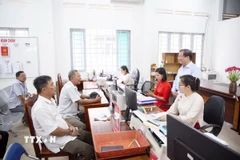 Phó Chủ tịch Ủy ban Nhân dân tỉnh Tây Ninh Nguyễn Hồng Thanh (đứng bên phải) lắng nghe ý kiến của nhân dân đến làm thủ tục hành chính tại Trung tâm phục vụ Hành chính công xã Tân Đông. (Ảnh: Giang Phương/TTXVN)