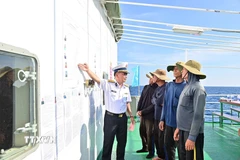 Đại tá Lê Hồng Quang, Phó Chủ nhiệm Chính trị Vùng 2 Hải quân, Tổ trưởng Tổ bầu cử sớm trên biển hướng dẫn cho ngư dân tàu cá QNg 96435 TS nắm thể lệ bầu cử. (Ảnh: TTXVN phát)