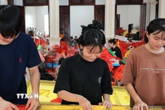 Từng công đoạn, từng lá cờ được người dân nơi đây thực hiện một cách tỉ mỉ. (Ảnh: Lê Đông/TTXVN)