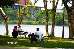 Người dân đến công viên bờ Bắc sông Hương, thành phố Huế để hóng mát, tránh nắng nóng gay gắt. (Ảnh: Nguyên Lý/TTXVN)