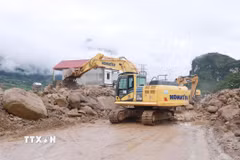 Các phương tiện máy móc tập trung san gạt cây cối, đất đá góp phần thông đường tạm thời cho nhân dân đi lại. (Ảnh: Quý Trung/TTXVN)