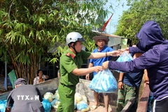 Lực lượng tại chỗ phối hợp với các nhóm thiện nguyện phân phối thức ăn cho các người dân vùng ngập Hàm Thắng. (Ảnh: Hồng Hiếu/TTXVN)