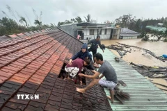 Lũ dâng cao, người dân phải phá mái nhà leo lên để tránh nguy hiểm. (Ảnh: TTXVN phát)