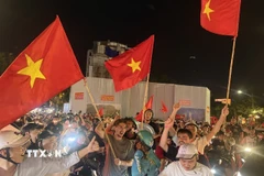 Người dân mang theo cờ Tổ quốc diễu hành trên các tuyến phố Hà Nội để mừng chiến thắng. (Ảnh: An Đăng/TTXVN)