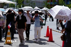 Người dân di chuyển trên đường phố dưới trời nắng nóng tại Osaka, Nhật Bản. (Ảnh: THX/TTXVN)