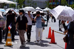 Người dân di chuyển trên đường phố dưới trời nắng nóng tại Osaka, Nhật Bản. (Ảnh: THX/TTXVN)