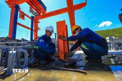 Công nhân thi công lắp đặt cấu kiện trên mái đập. (Ảnh: Trọng Đạt/TTXVN)