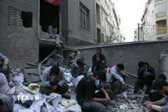 Người dân ngồi trên đống đổ nát của những tòa nhà bị phá hủy do xung đột tại Tehran, Iran ngày 15/3/2026. (Ảnh: THX/TTXVN)