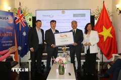 Giáo sư Nghiêm Đức Long (thứ hai, trái sang), Chủ tịch VASEA trao tượng trưng số tiền quyên góp ủng hộ đồng bào vùng bão lũ cho đại diện Tổng Lãnh sự Việt Nam tại Sydney Nguyễn Thanh Tùng. (Ảnh: Thanh Tú/TTXVN)