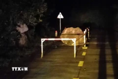 Tảng đá lớn lăn xuống từ vách núi, nằm chắn một phần mặt đường Hồ Chí Minh nhánh Tây. (Ảnh: TTXVN phát)