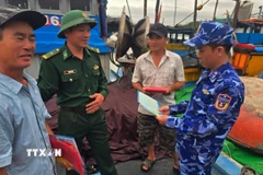 Cán bộ Vùng Cảnh sát biển 2 phối hợp với các lực lượng chức năng phổ biến các quy của pháp luật trong khai thác hải sản cho ngư dân. (Ảnh: Đoàn Hữu Trung/TTXVN)