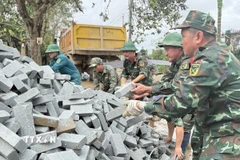 Chiến sỹ Đoàn Kinh tế-Quốc phòng 207/Quân khu 5 vận chuyển vật liệu xây sửa nhà cho người dân. (Ảnh: Tường Quân/TTXVN)