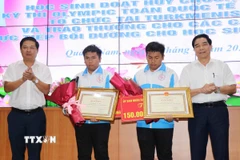 Bí thư Tỉnh ủy Quảng Nam Lương Nguyễn Minh Triết và Chủ tịch Ủy ban Nhân dân tỉnh Quảng Nam Lê Văn Dũng tặng Bằng khen và hoa cho hai anh em Nguyễn Trí Hiền và Nguyễn Trí Hậu. (Ảnh: Đoàn Hữu Trung/TTXVN)