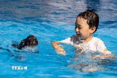 Em nhỏ tránh nóng dưới bể bơi cùng thú cưng tại Seoul, Hàn Quốc. (Ảnh: THX/TTXVN phát)