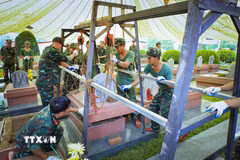 Phần nắp mộ liệt sỹ được nâng lên bằng hệ thống pa lăng xích. Đây là một trong những sáng kiến trong quá trình khai quật lấy mẫu của cán bộ, chiến sỹ Bộ Chỉ huy Quân sự tỉnh Điện Biên. (Ảnh: Xuân Tư/TTXVN)