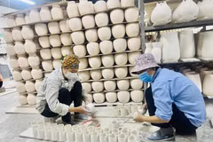 Những người thợ gốm Bát Tràng với những sản phẩm được làm tại xưởng gốm Bát Tràng (Hà Nội). (Ảnh: Tuyết Mai/TTXVN)