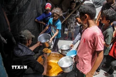 Các em nhỏ nhận thực phẩm cứu trợ tại Jabalia, Dải Gaza. (Ảnh: THX/TTXVN)