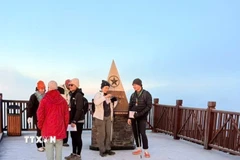 Du khách thích thú khi được trải nghiệm băng giá trên đỉnh Fansipan. (Ảnh: TTXVN phát)