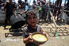 Em nhỏ Palestine nhận thức ăn cứu trợ tại thành phố Gaza, ngày 24/7/2025. (Ảnh: THX/TTXVN)