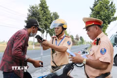 Cảnh sát giao thông kiểm tra nồng độ cồn. (Ảnh minh họa. Văn Sĩ/TTXVN)