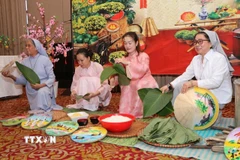 Các sơ cùng đại diện cộng đồng mô phỏng nét đẹp gói bánh chưng tại buổi lễ. (Ảnh: TTXVN phát)