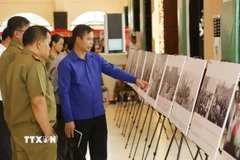 Cán bộ Đoàn và sỹ quan công an Lào tham quan khu trưng bày ảnh về Chiến dịch Hồ Chí Minh lịch sử của Việt Nam. (Ảnh: Xuân Tú/TTXVN)