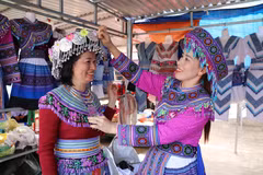 Du khách trải nghiệm mặc trang phục truyền thống của đồng bào Mông tại chợ phiên Đắk R’măng (xã Tà Đùng, tỉnh Lâm Đồng). (Ảnh: Nguyễn Huy Thành/TTXVN)