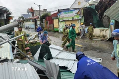 Các lực lượng, chính quyền xã giúp người dân dọn dẹp nhà bị sập, tốc mái ở xã Hoằng Giang. (Ảnh: Việt Hoàng/TTXVN)