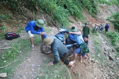 Lực lượng chức năng trong hành trình vượt qua các điểm mặt đường bị đứt gãy, sụt trượt xuống sâu hơn 2m để đến bản Na Ngân bị cô lập. (Ảnh: Xuân Tiến/TTXVN)