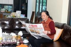 Đảng viên Vũ Thị Tuyết, thôn Chằm Vải, xã Thanh Bình, theo dõi thông tin về công tác chuẩn bị Đại hội Đảng XIV trên báo chí. (Ảnh: Nguyễn Chinh/TTXVN)